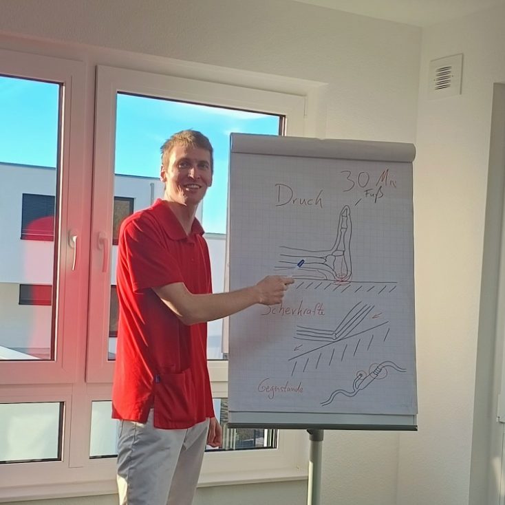 Tagungsraum mit Tischen, Stühlen und dekorativen Blumen in Vasen.